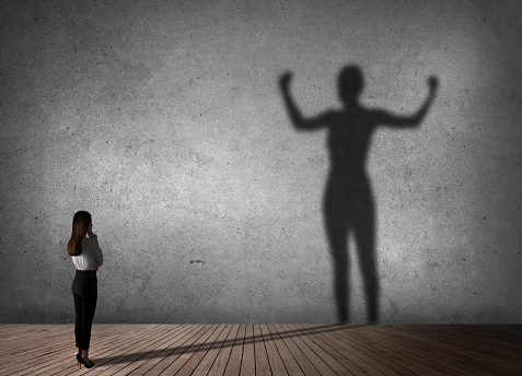 A woman standing in front of a wall with her shadow on it.