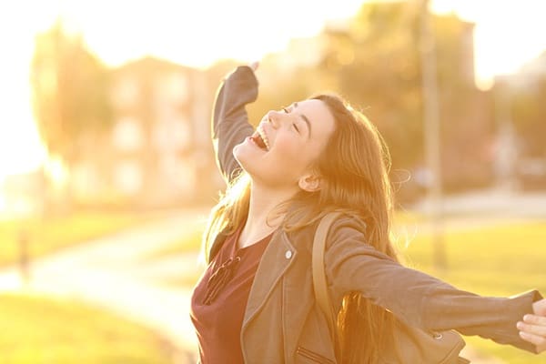 A woman standing outside with her arms outstretched.