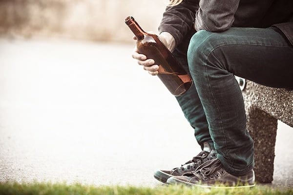 A person sitting on the ground holding onto a bottle