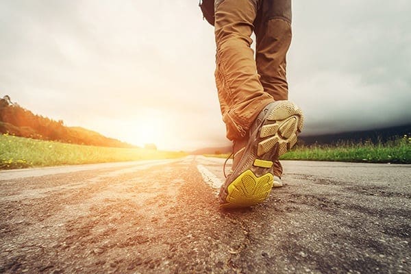 A person walking on the road with their shoes off