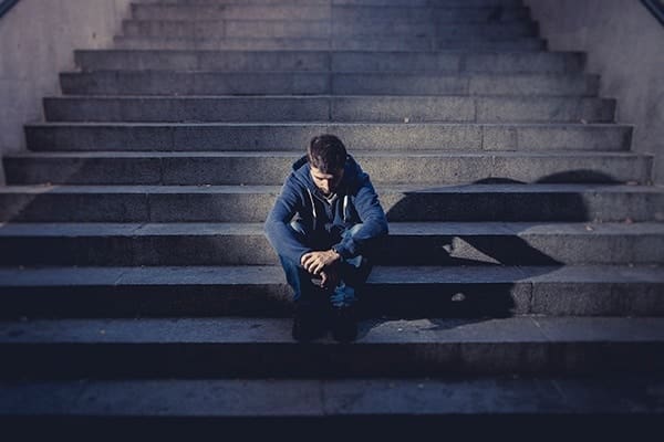 A man sitting on the steps of an outdoor staircase.