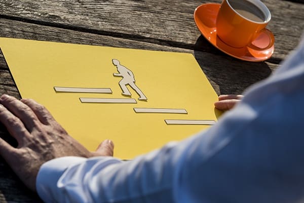 A person sitting at the table with an orange cup.