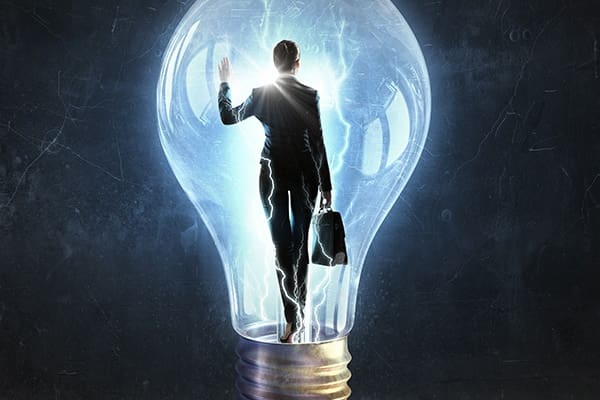 A man in suit and tie standing inside of a light bulb.