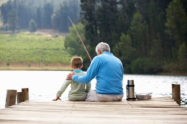 A man and boy fishing on the dock.