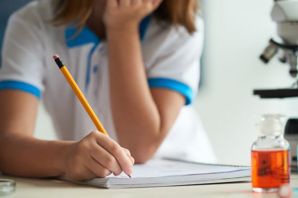 A person writing on paper with a pencil