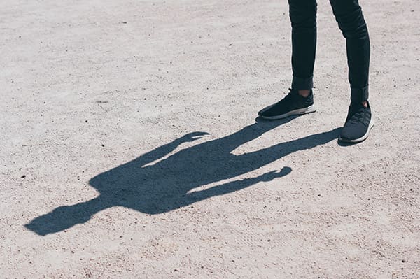 A person standing on the ground with their shadow