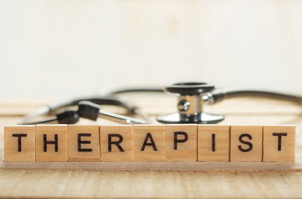 A stethoscope is sitting on top of the word therapis.