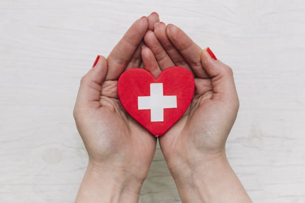 A person holding a heart with a cross on it.