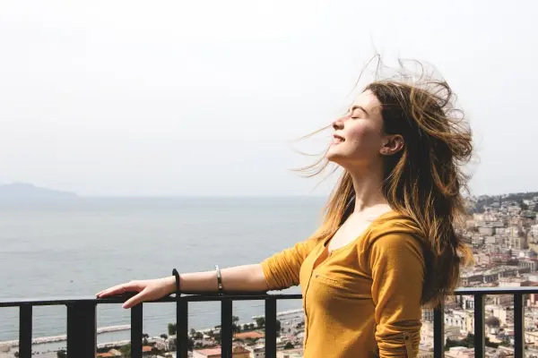 A woman standing on top of a balcony near the ocean.