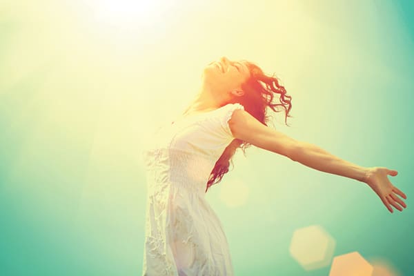 A woman in white dress holding her arms out.