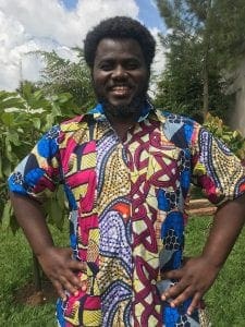 A man in colorful shirt standing outside with hands on hips.