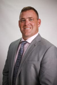 A man in a suit and tie smiling for the camera.