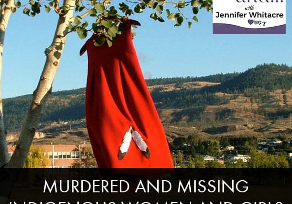 A red umbrella hanging from a tree in front of the mountains.