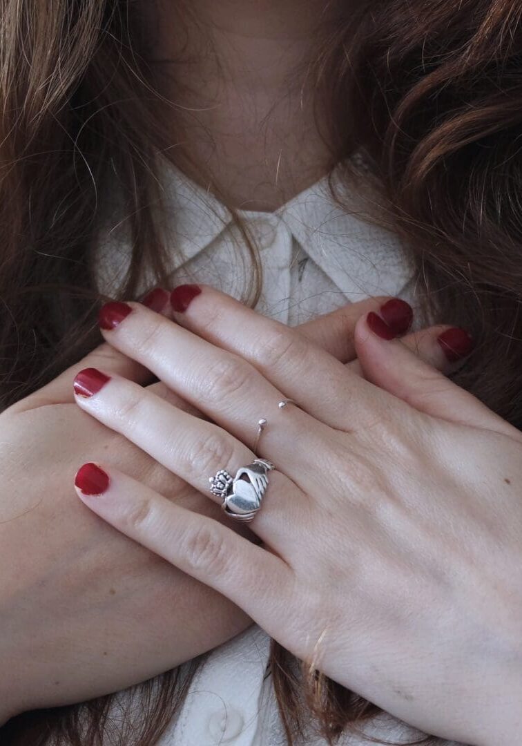 A woman with red nails holding her hands over her chest.